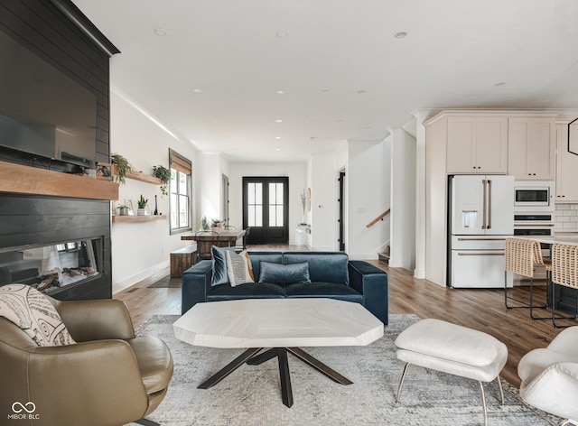 living area featuring stairs, recessed lighting, a multi sided fireplace, and light wood-style floors