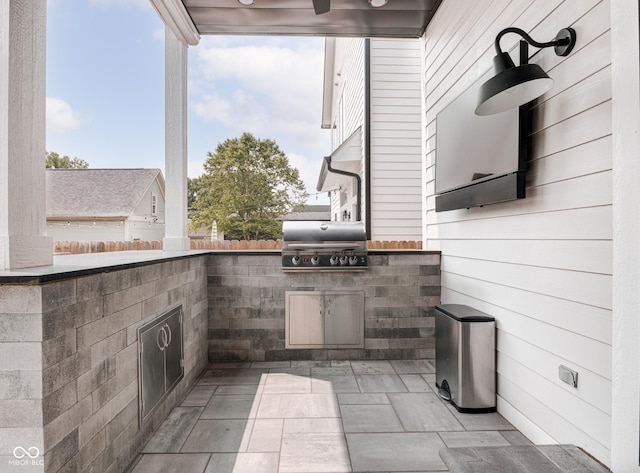 view of patio featuring exterior kitchen, area for grilling, and a ceiling fan