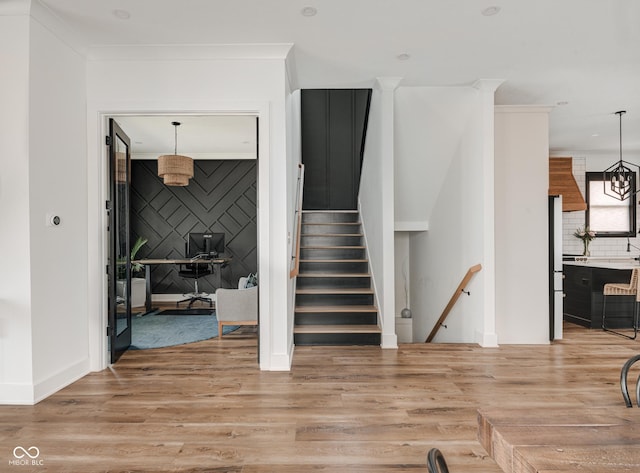 stairway featuring baseboards, an accent wall, ornamental molding, and wood finished floors