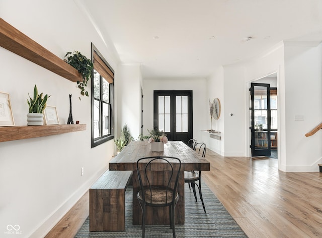 dining room featuring stairway, light wood-type flooring, and a wealth of natural light