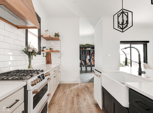 kitchen with pendant lighting, light countertops, custom range hood, and white range with gas stovetop