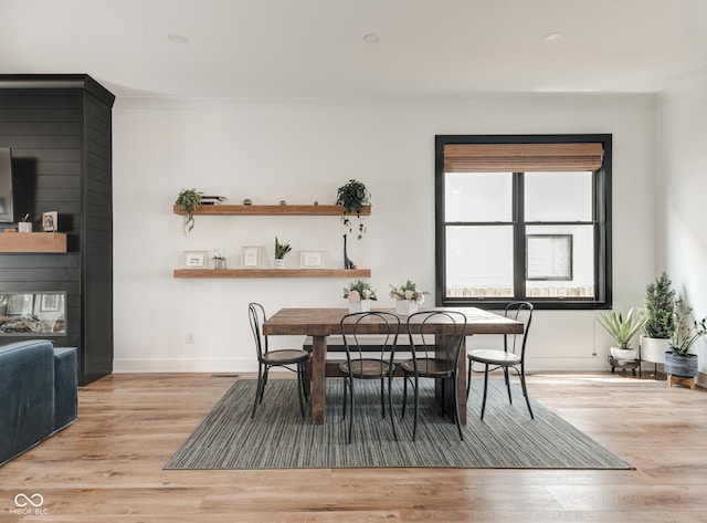 dining area with ornamental molding, light wood-style flooring, and baseboards