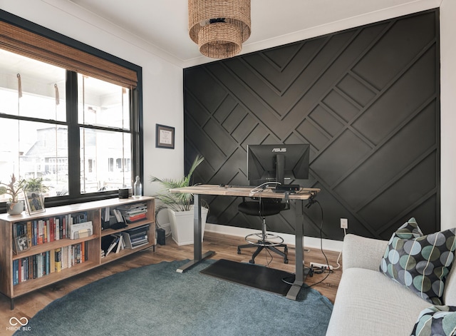 office space featuring baseboards, an accent wall, ornamental molding, and wood finished floors