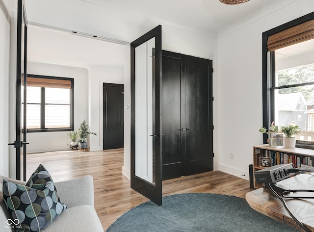 foyer with light wood-style floors, ornamental molding, and baseboards