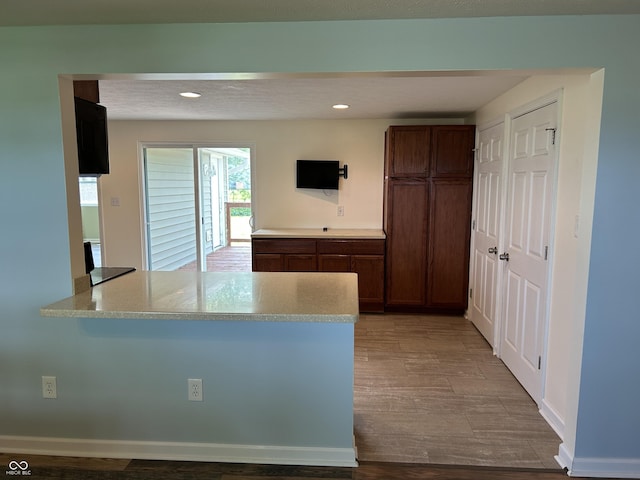 kitchen featuring recessed lighting, light countertops, a peninsula, and wood finished floors