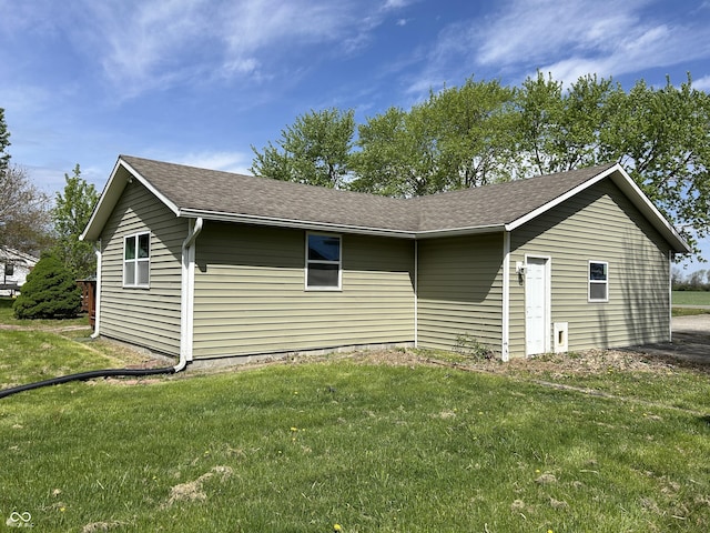 view of property exterior with a shingled roof and a yard
