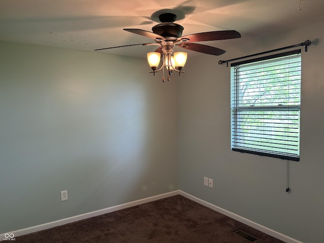 empty room featuring baseboards, a ceiling fan, dark colored carpet, and visible vents