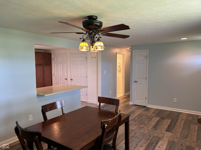 dining area featuring baseboards, a ceiling fan, dark wood finished floors, and a textured ceiling