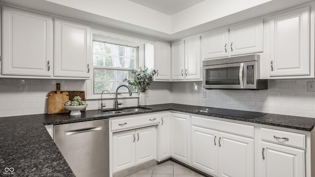 kitchen featuring tasteful backsplash, white cabinets, stainless steel appliances, and a sink