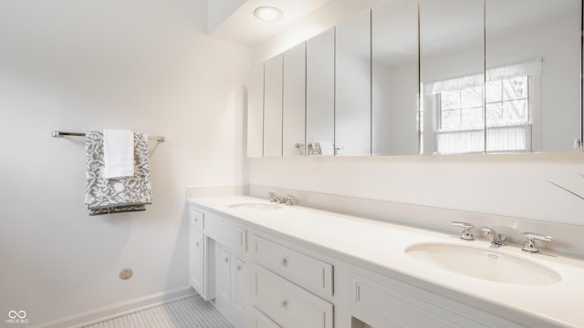 bathroom with double vanity, tile patterned flooring, baseboards, and a sink