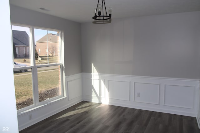 unfurnished dining area with dark hardwood / wood-style flooring and an inviting chandelier