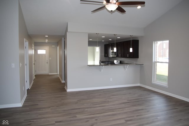 kitchen featuring dark brown cabinetry, a breakfast bar area, dark hardwood / wood-style flooring, kitchen peninsula, and ceiling fan