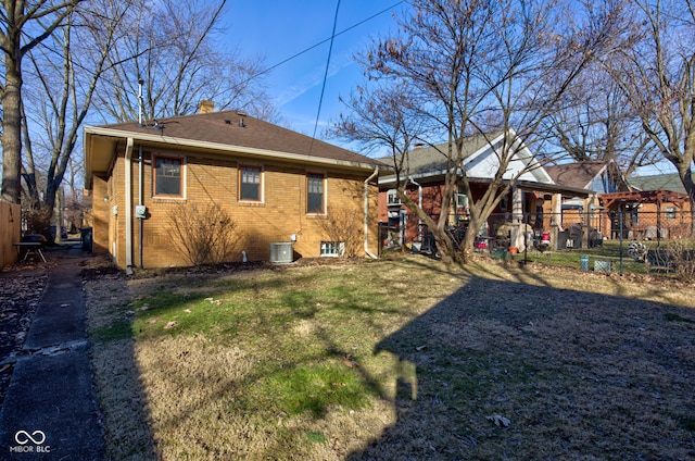 rear view of property featuring central AC and a lawn