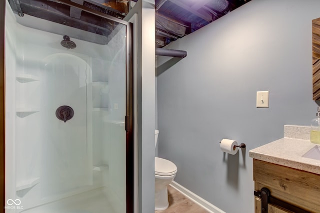 bathroom featuring a shower with door, vanity, and toilet