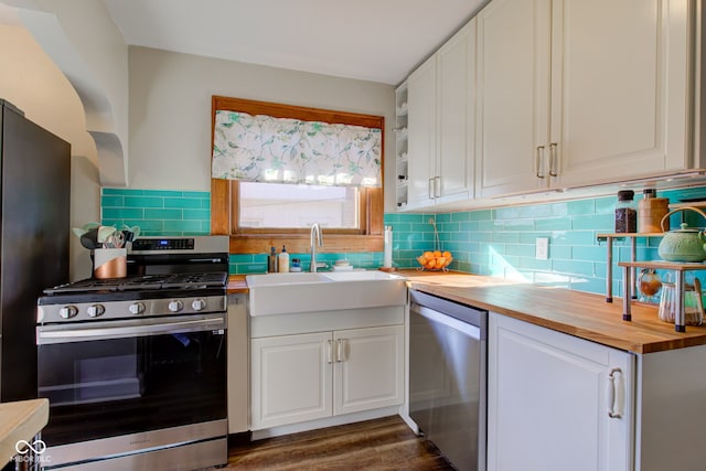 kitchen with white cabinetry, appliances with stainless steel finishes, butcher block counters, and sink