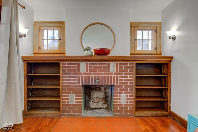 unfurnished living room featuring wood-type flooring and a brick fireplace