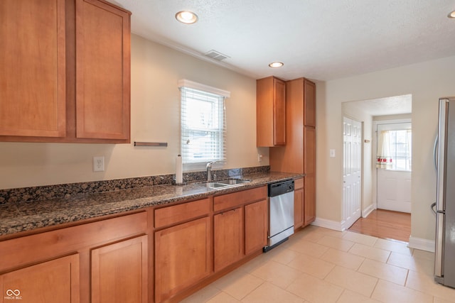 kitchen with stainless steel appliances, sink, and dark stone countertops