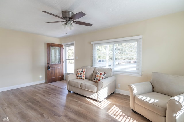 living room with ceiling fan, a textured ceiling, light hardwood / wood-style flooring, and a healthy amount of sunlight