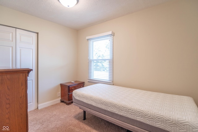 bedroom featuring light carpet and a textured ceiling