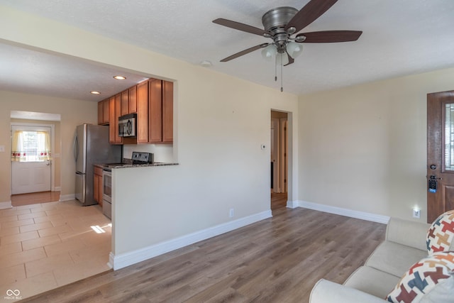 unfurnished living room featuring ceiling fan, light hardwood / wood-style floors, and a textured ceiling