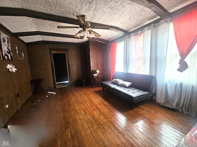 unfurnished room featuring hardwood / wood-style flooring, ceiling fan, beam ceiling, and a textured ceiling