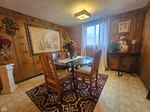 dining space with wooden walls and a textured ceiling