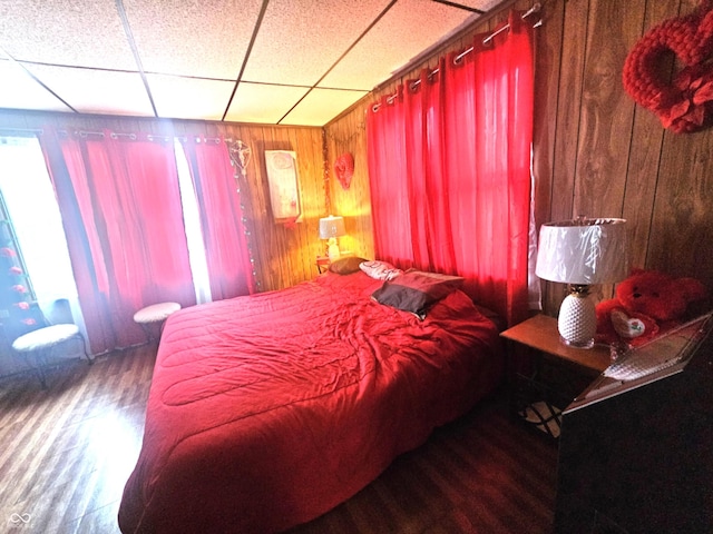 bedroom with wood-type flooring, a paneled ceiling, and wood walls