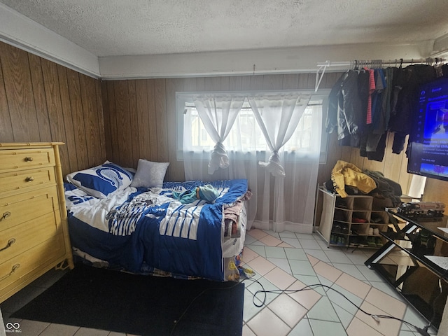 bedroom featuring wooden walls and a textured ceiling