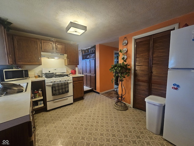 kitchen featuring sink, a textured ceiling, and white appliances