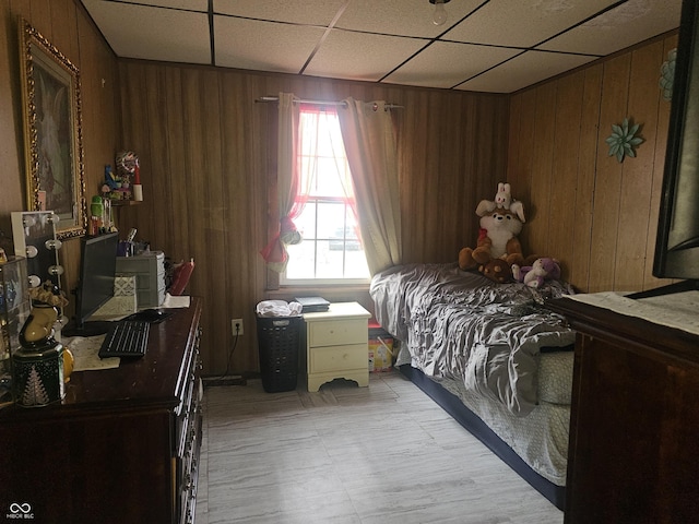 bedroom featuring a drop ceiling and wood walls