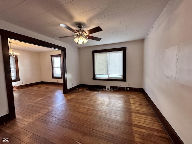 empty room with ceiling fan with notable chandelier and dark wood-type flooring