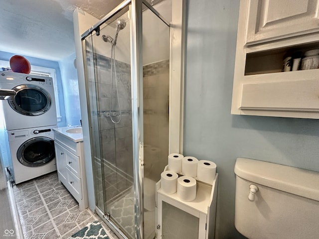 bathroom featuring walk in shower, stacked washer / drying machine, toilet, and vanity