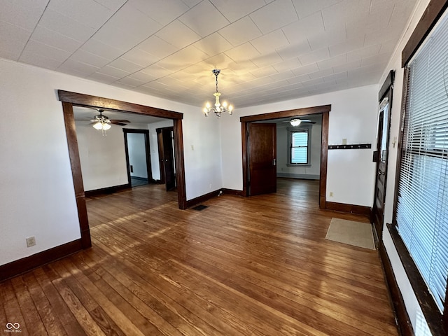 spare room with dark hardwood / wood-style floors and ceiling fan with notable chandelier