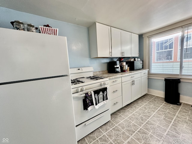 kitchen with white appliances, white cabinets, and light tile patterned flooring