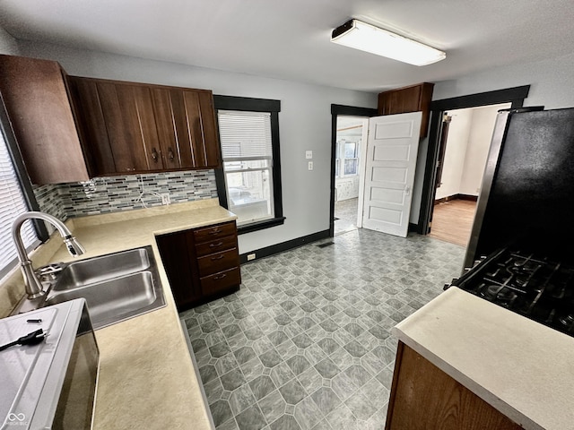 kitchen featuring dark brown cabinetry, sink, tasteful backsplash, and stainless steel fridge