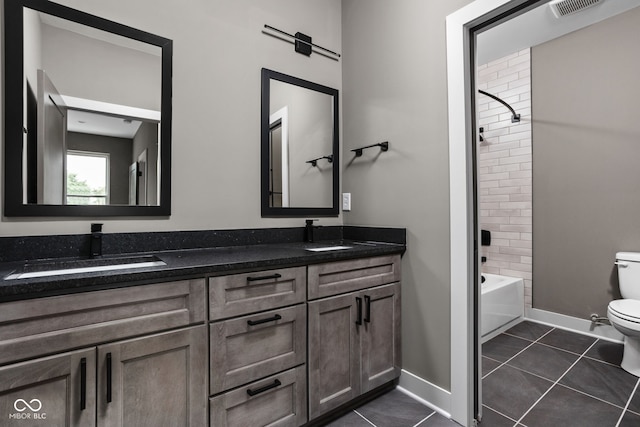 full bathroom with tile patterned flooring, vanity, tiled shower / bath, and toilet