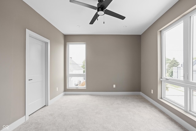 unfurnished room featuring light carpet, ceiling fan, and a healthy amount of sunlight