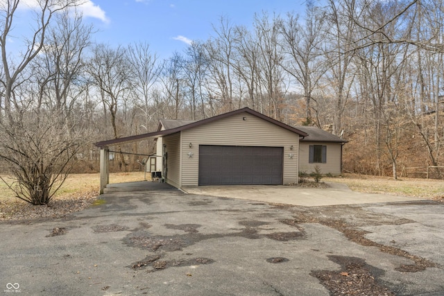 view of side of property featuring a carport, an attached garage, and driveway