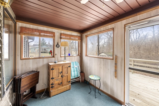 sitting room with carpet floors, wooden ceiling, baseboards, and wood walls