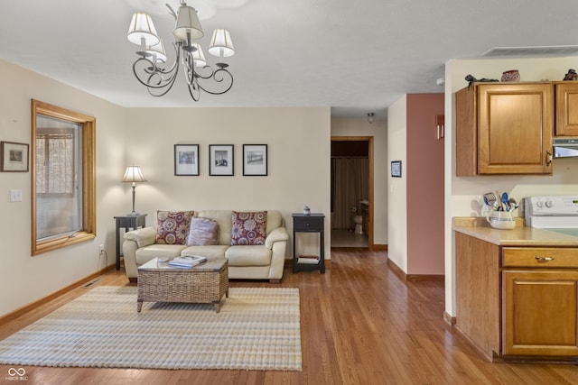 living area featuring an inviting chandelier, baseboards, visible vents, and wood finished floors