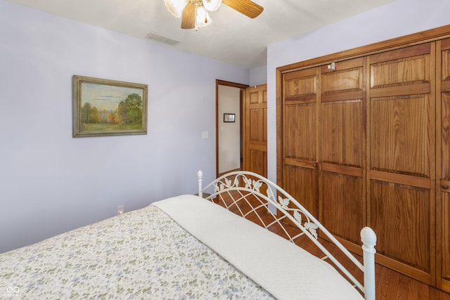 bedroom featuring ceiling fan, visible vents, a closet, and wood finished floors