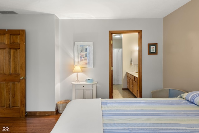 bedroom featuring visible vents, ensuite bath, light wood-style flooring, and baseboards