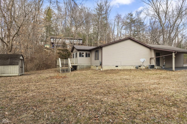 rear view of house with a lawn, an outbuilding, crawl space, a storage unit, and a deck