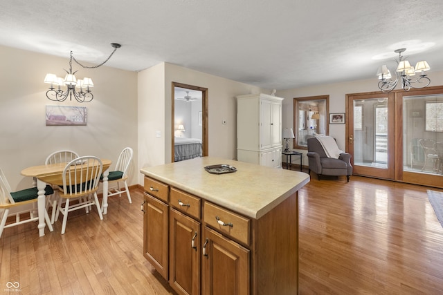 kitchen featuring light wood finished floors, brown cabinets, a center island, and a notable chandelier