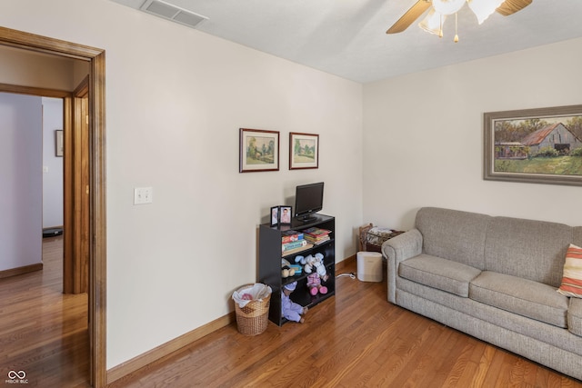 living room featuring ceiling fan, wood finished floors, visible vents, and baseboards