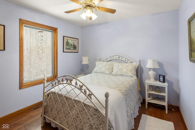 bedroom featuring ceiling fan, wood finished floors, visible vents, and baseboards