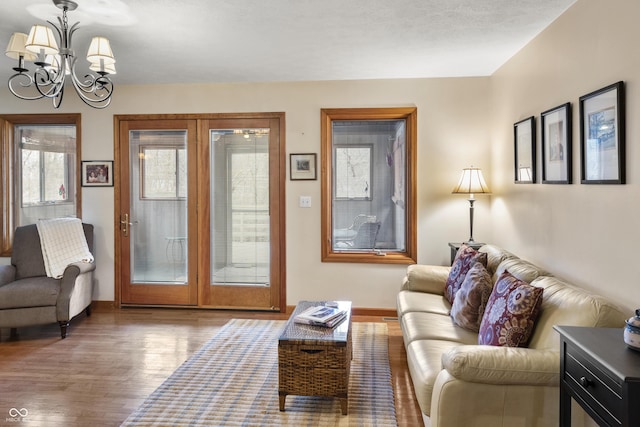 living room featuring a chandelier, baseboards, and wood finished floors