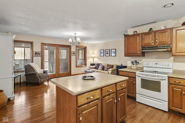 kitchen with white electric stove, visible vents, light wood-style floors, open floor plan, and under cabinet range hood