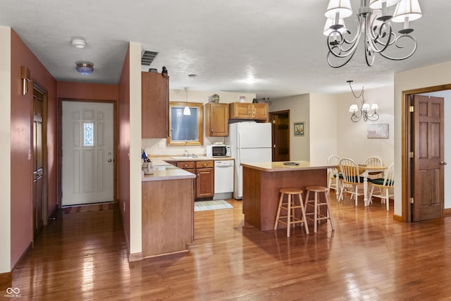 kitchen featuring a center island, visible vents, light wood-style flooring, an inviting chandelier, and white appliances