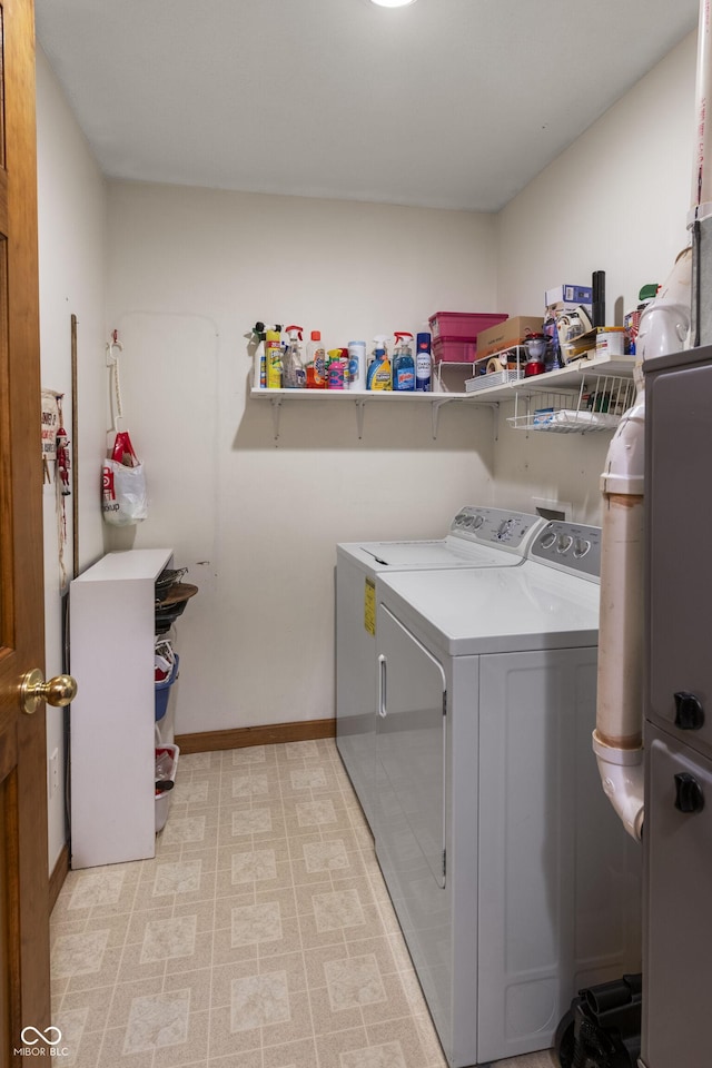 clothes washing area with laundry area, washer and clothes dryer, and baseboards